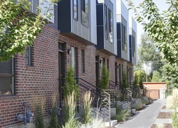 a red brick building with black windows and a sidewalk at BlueKoi Townhomes for rent in Salt Lake City, UT