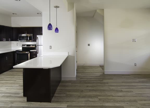 a view of a kitchen and living room with white walls and wood flooring at BlueKoi Townhomes for rent in Salt Lake City, UT