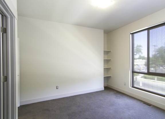 an empty living room with a large window and white walls at BlueKoi Townhomes for rent in Salt Lake City, UT
