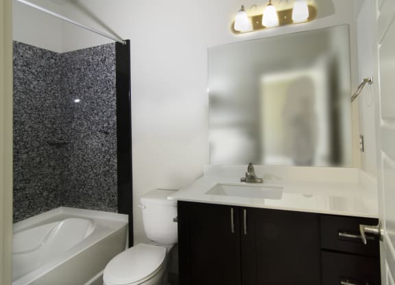 a bathroom with a sink, toilet and mirror and a tub at BlueKoi Townhomes for rent in Salt Lake City, UT