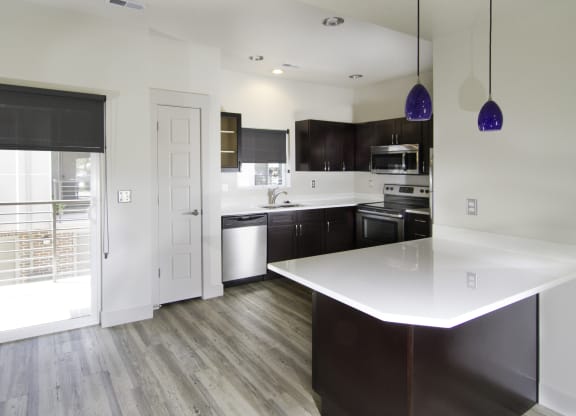 a kitchen with a white counter top and a sliding glass door at BlueKoi Townhomes for rent in Salt Lake City, UT
