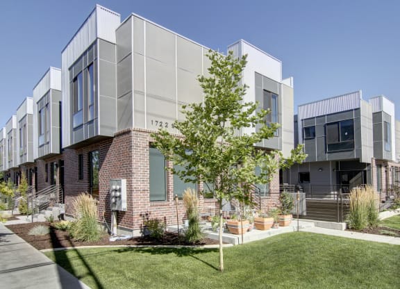 the exterior of an apartment building with grass and a tree at BlueKoi Townhomes for rent in Salt Lake City, UT