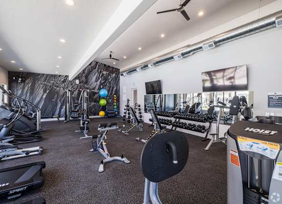 A gym with a variety of equipment including treadmills, weights, and exercise machines.