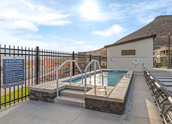 A pool area with a caution sign and a hot tub.