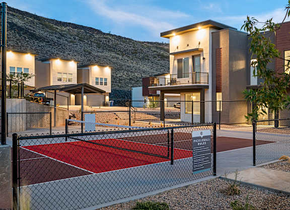 A pickleball court is located in front of a modern apartment complex.