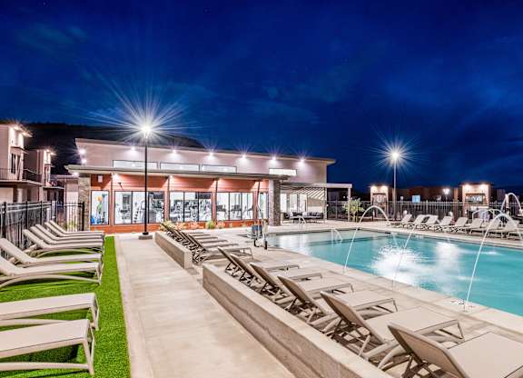 A poolside area with lounge chairs and a building in the background.