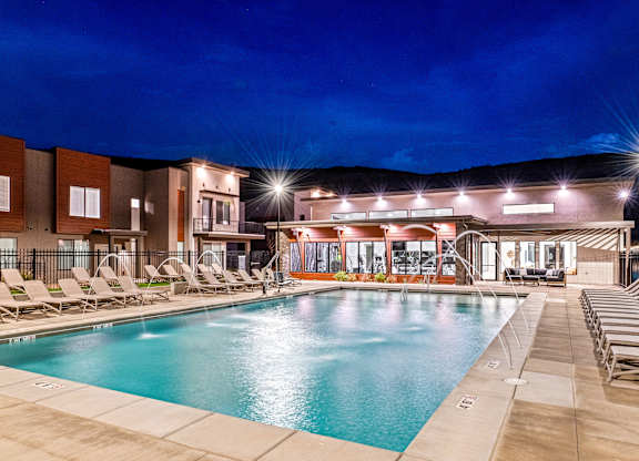 A swimming pool area with lounge chairs and a building in the background.