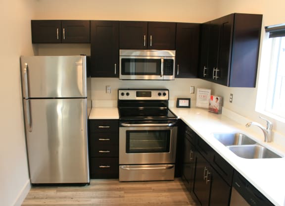an empty kitchen with stainless steel appliances and black cabinets at BlueKoi Townhomes for rent in Salt Lake City, UT