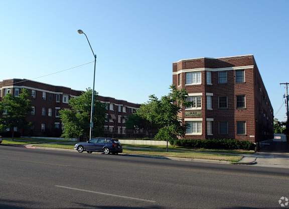 A street view of a residential area with cars parked on the side of the road.