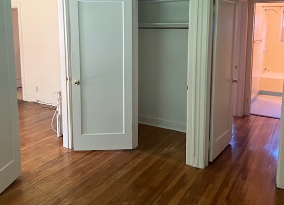 A room with a white door and wooden floors.