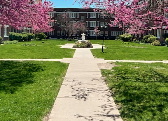 A pathway leads through a grassy area with a building in the background.