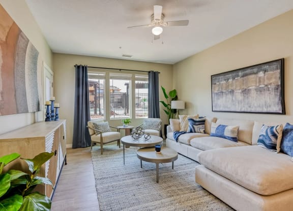 a spacious, modern living room with furniture and a ceiling fan at Brookfield Apartments for rent in St. George, UT.