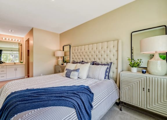a beautiful bedroom with a large bed and mirror at Brookfield Apartments for rent in St. George, UT.