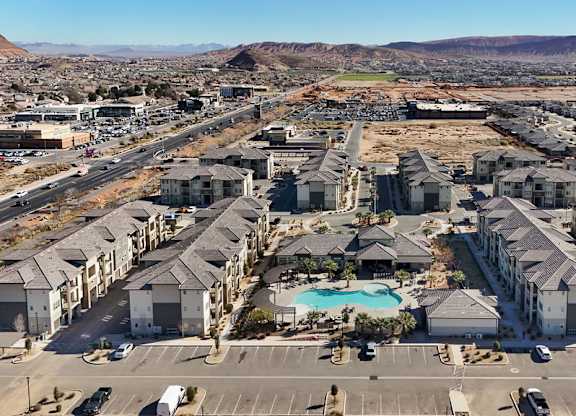 A large apartment complex with a pool in the middle of a parking lot.