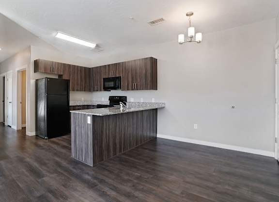 A kitchen with a black fridge and microwave, a wooden counter, and a black stove.