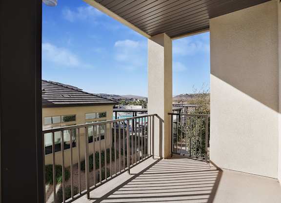 A balcony with a metal railing and a view of the sky and buildings.