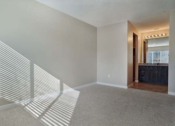 A room with a carpeted floor and a window with blinds.