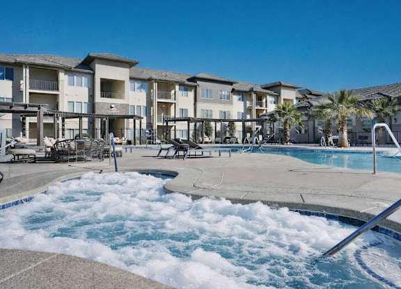 A large swimming pool with a hot tub in the middle of a resort.