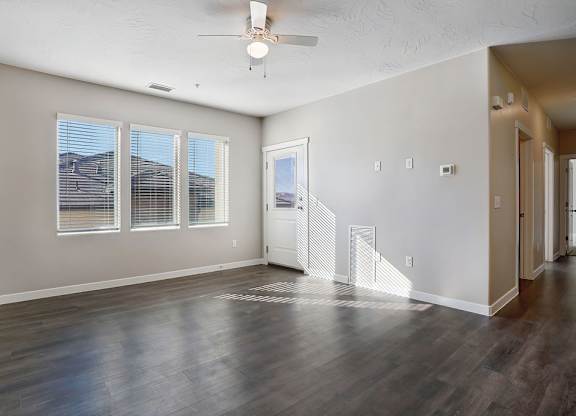 Empty room with wooden floors and a ceiling fan.