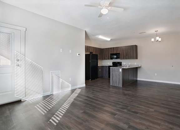 A kitchen with a dark wood floor and white walls.