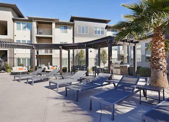 A palm tree stands in front of a building with a patio area.
