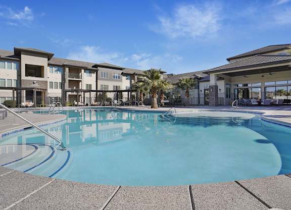A large swimming pool in front of a building with a clear blue sky.
