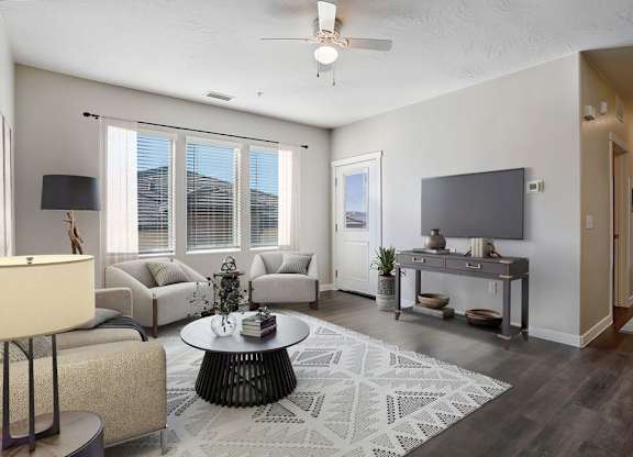 A living room with a large window, a flat screen TV, and a rug on the floor.