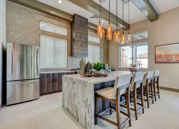 a large, modern kitchen with a large island with a marble counter top and stainless steel appliances at the clubhouse in Brookfield Apartments for rent in St. George, UT.