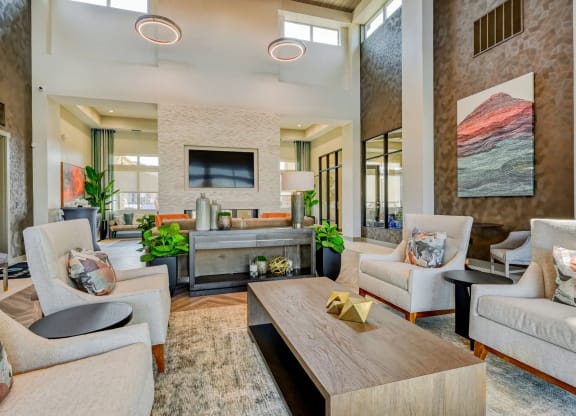 a spacious, modern living room with couches and chairs and a table in the clubhouse at Brookfield Apartments in St. George, UT.
