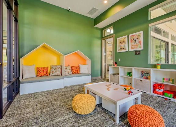 a children's play room with green walls and a table, chairs and toys at Brookfield Apartments for rent in St. George, UT.