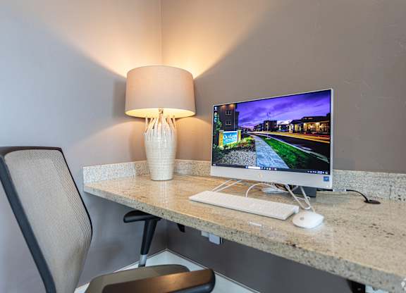 A modern workspace with a computer, keyboard, mouse, and lamp.