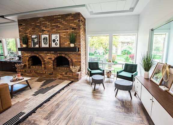 A living room with a brick fireplace and a green chair.