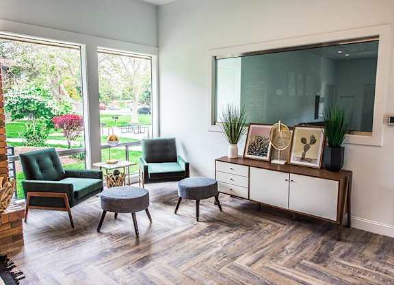 A living room with a green chair and a grey ottoman.