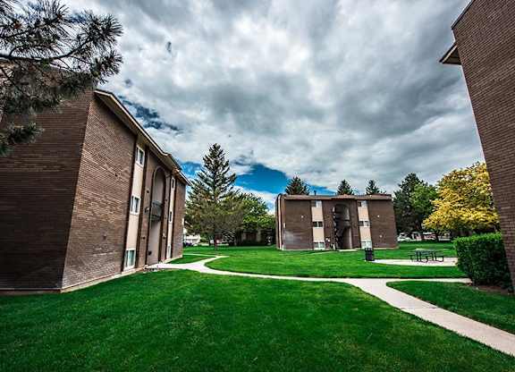 A grassy area with a pathway and two buildings on either side.