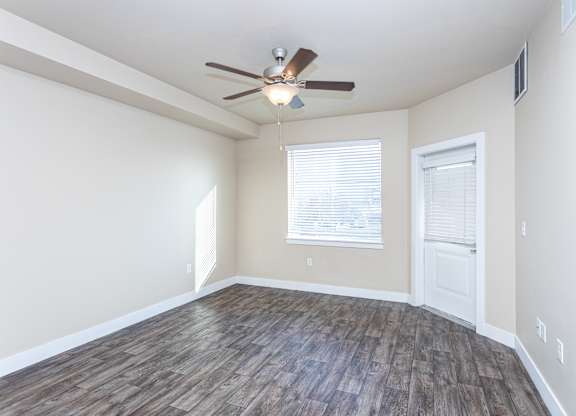 A room with a ceiling fan and wooden flooring.