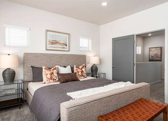 A bedroom with a large bed and a bench.