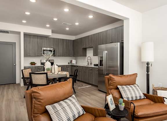 A modern kitchen with brown leather couches and a wooden floor.