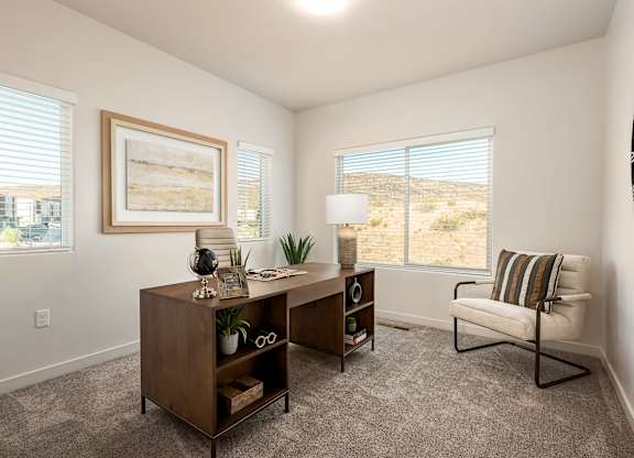 A room with a chair, a desk, and a painting on the wall.