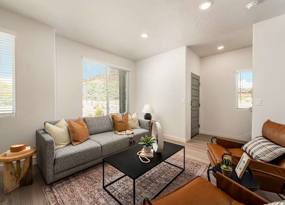 A living room with a grey couch, a black coffee table, and a brown leather chair.