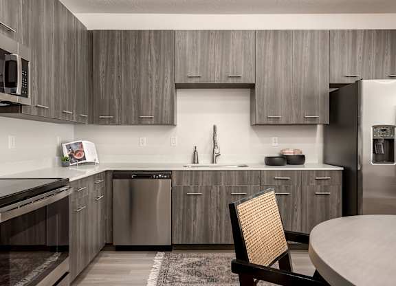 A modern kitchen with a wooden chair and stainless steel appliances.