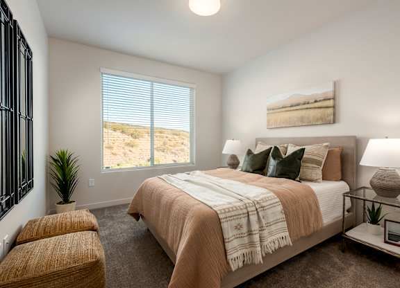 A bedroom with a large bed and a window overlooking a desert landscape.