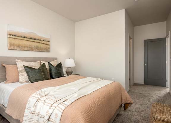 A bedroom with a bed, lamp, and painting on the wall.