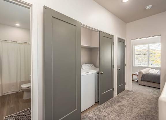 A small, modern bathroom with a washer and dryer built into the cabinetry.