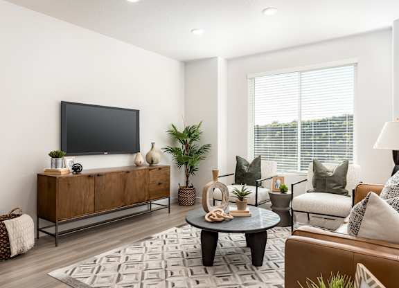 A modern living room with a flat screen TV, a wooden cabinet, a grey sofa, a coffee table, and a rug.