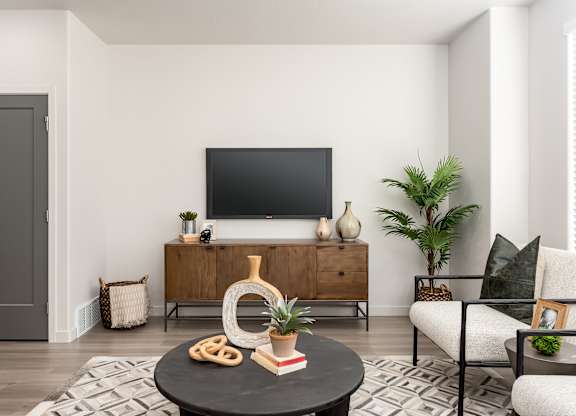 A living room with a flat screen TV mounted on the wall above a wooden cabinet.