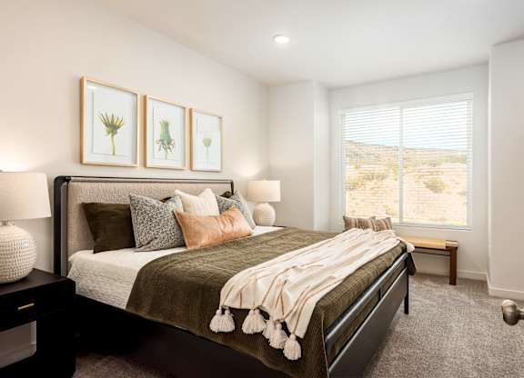 A bedroom with a large bed and a window overlooking a desert landscape.