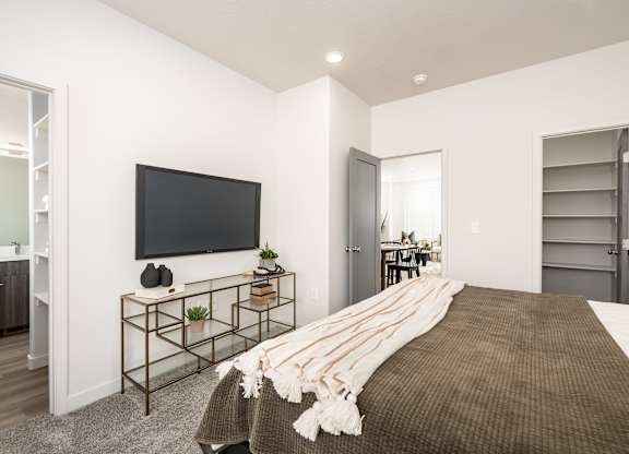 A bedroom with a large bed and a flat screen TV mounted on the wall.