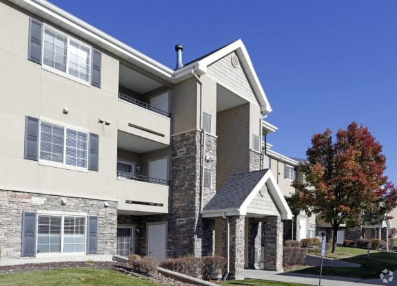 an exterior view of an apartment building with a lawn and trees