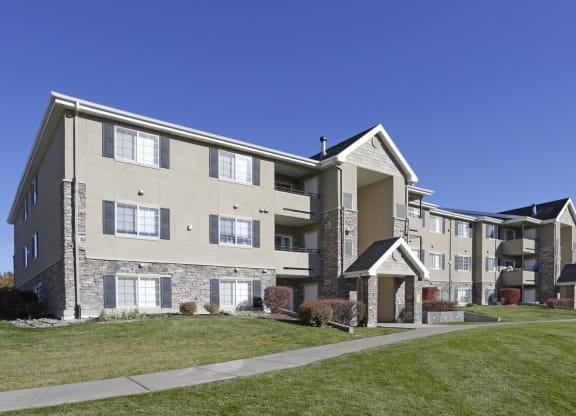 an exterior view of an apartment building with green grass and a sidewalk