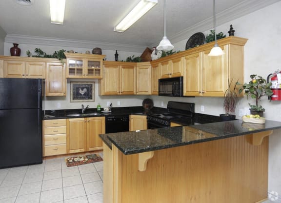 a kitchen with wooden cabinets and a black counter top